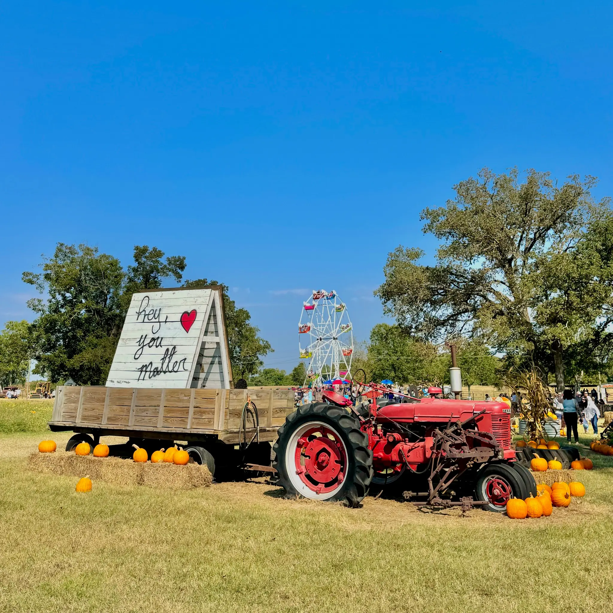 Red tractor with ferris wheel in background